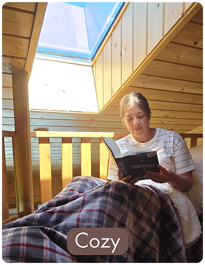 A women enjying reading a book in a blanket in bed.