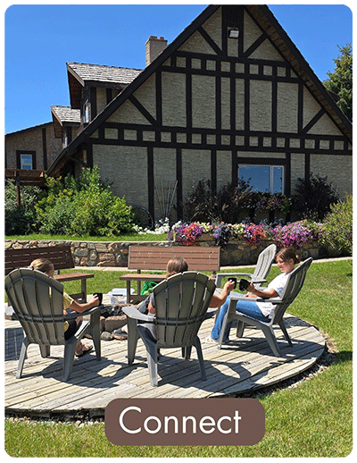 A mother and daughters chatting while sitting around the Rocky Ridge Country Lodge firepit patio on a sunny afternoon.