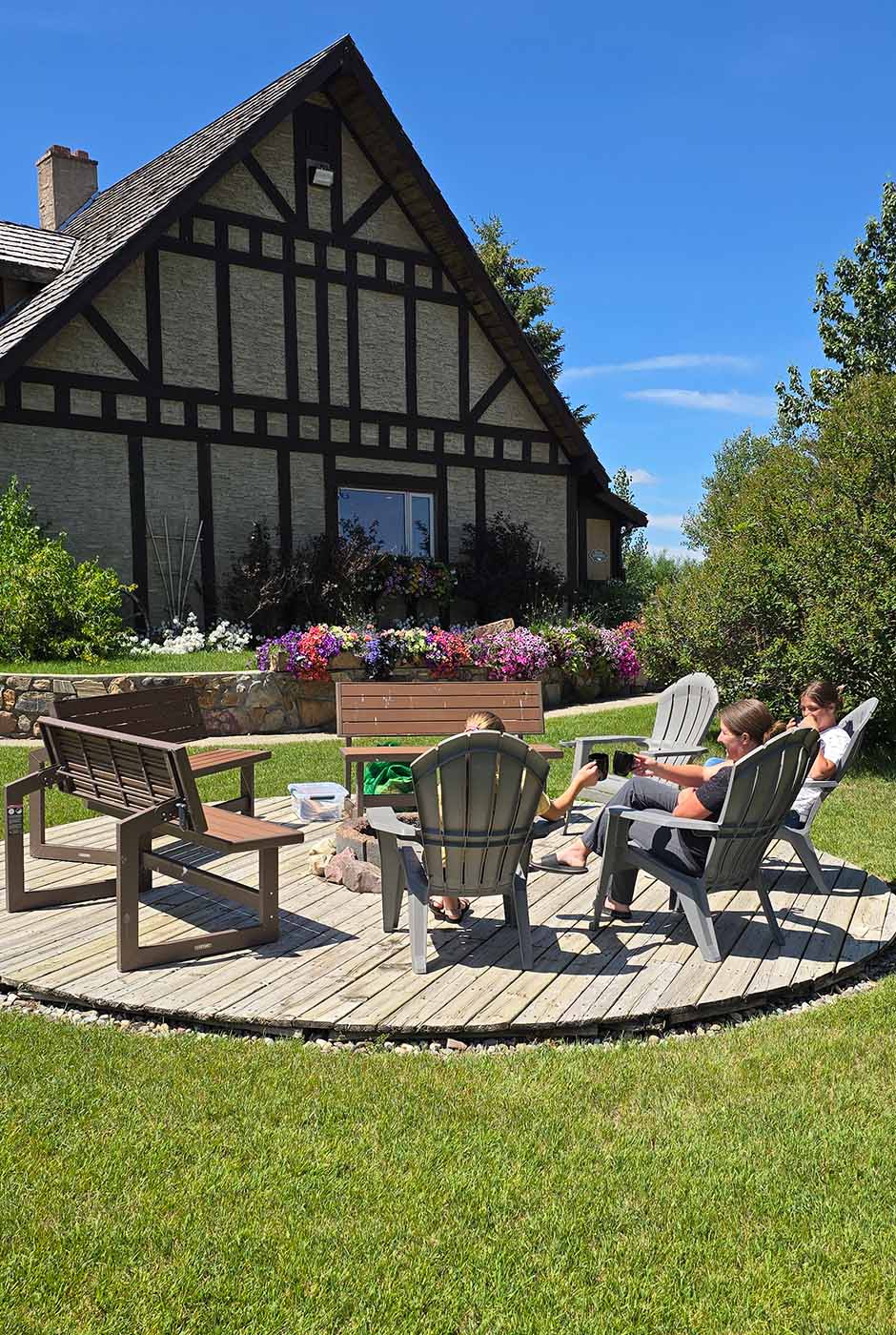 A mother and daughters chatting while sitting around the Rocky Ridge Country Lodge firepit patio on a sunny afternoon.